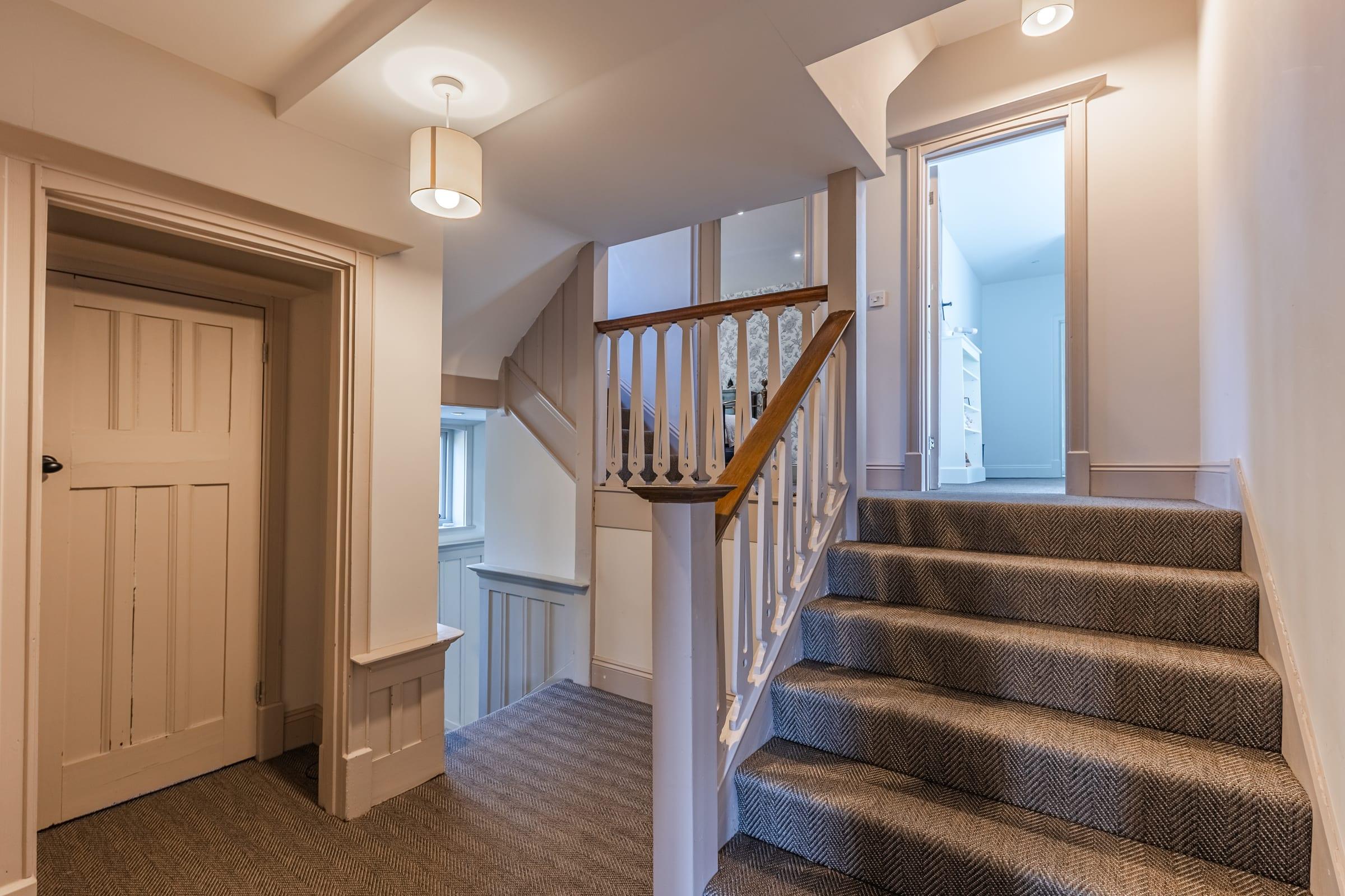 Herringbone underfoot, the staircase curving upward